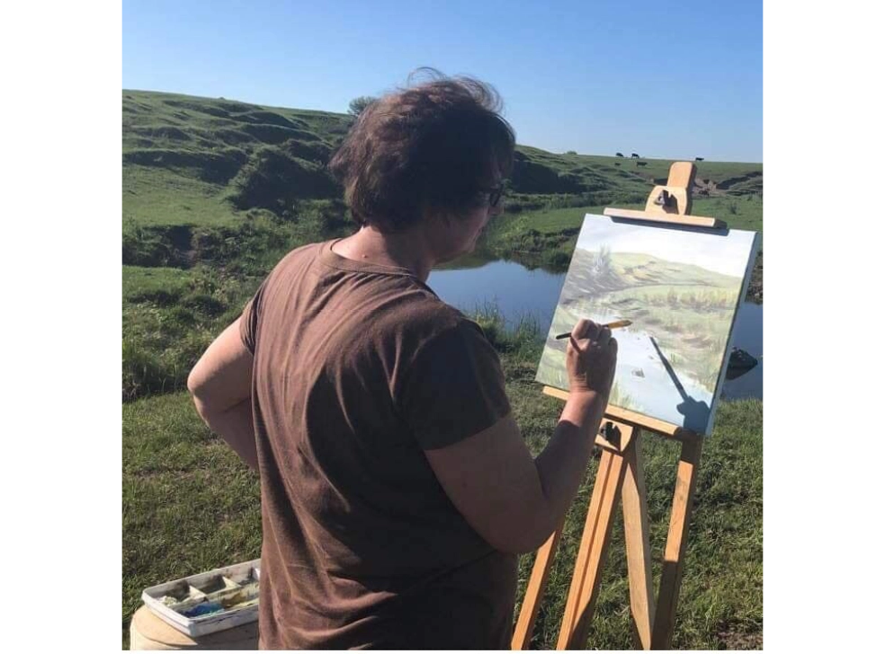 Artist painting a landscape on a canvas.